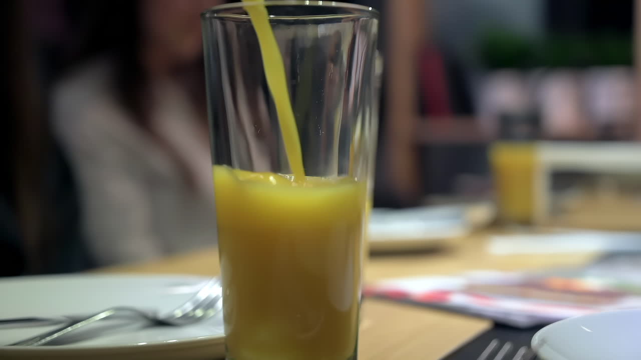 Primo piano di una donna che versa succo d'arancia in un bicchiere al ristorante
