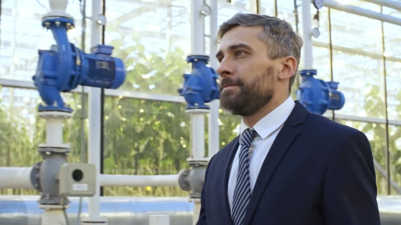 inversor masculino caminando en el invernadero industrial