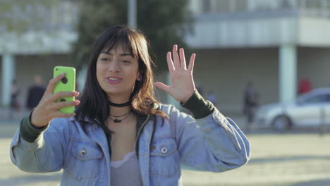 smiling teen girl waving to camera and showing thumb up.