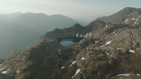 Stunning-overhead-drone-shot-of-an-emerald-green-mountain-lake-surrounded-by-rocky-cliffs-in-the-Austrian-Alps