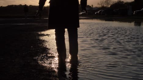 Silhouette-Einer-Person,-Die-Bei-Sonnenuntergang-In-Einer-Wasserpfütze-Planscht