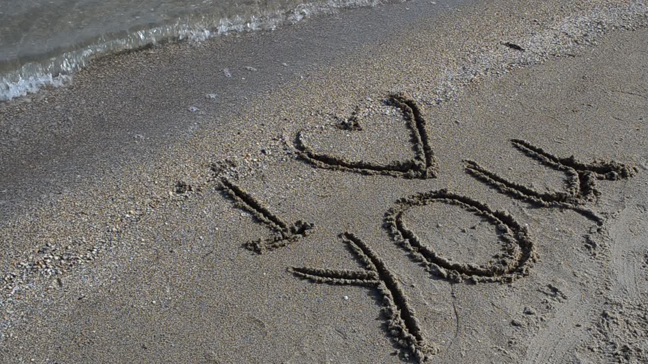 Inscription on the beach. Shooting on the beach. Shooting on the beach