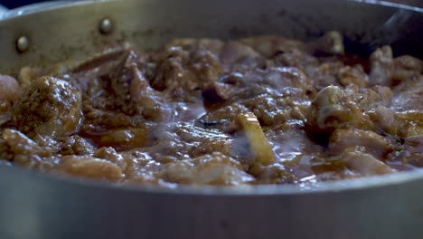 vista de cerca del curry de pollo a fuego lento con una rodaja de limón en una olla grande