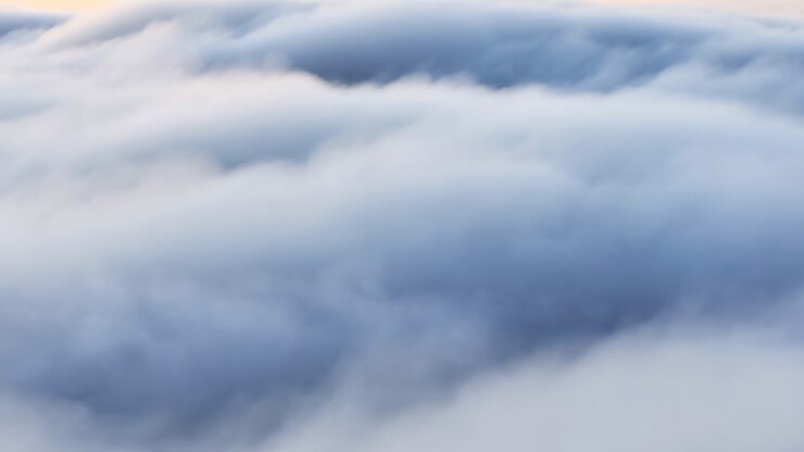 Soft Aerial View Of Clouds, Layered Mist And Pale Sunrise Glow, Drone Perspective Drifting Over Billowy White