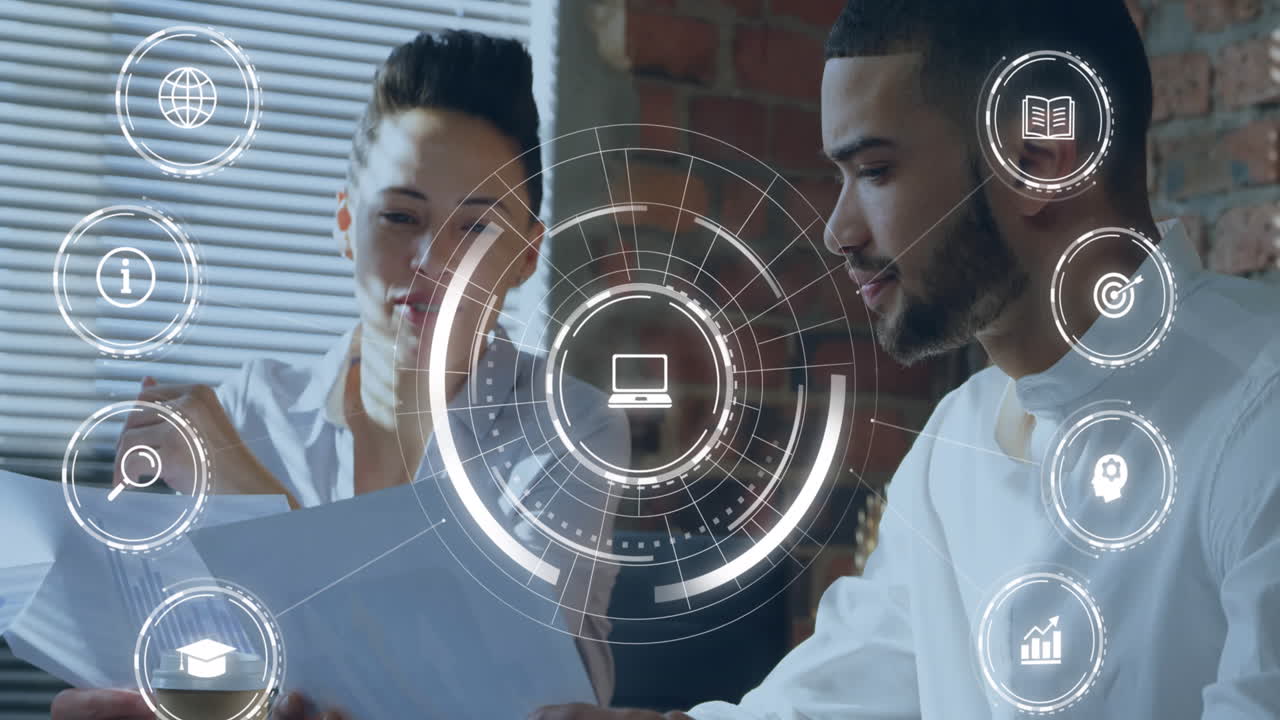 Animation of digital icons against diverse man and woman discussing over a document at office