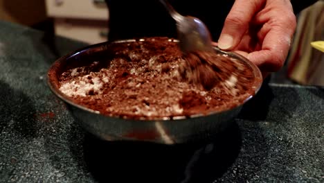 a person mixes the flour with chocolate powder to make a cake