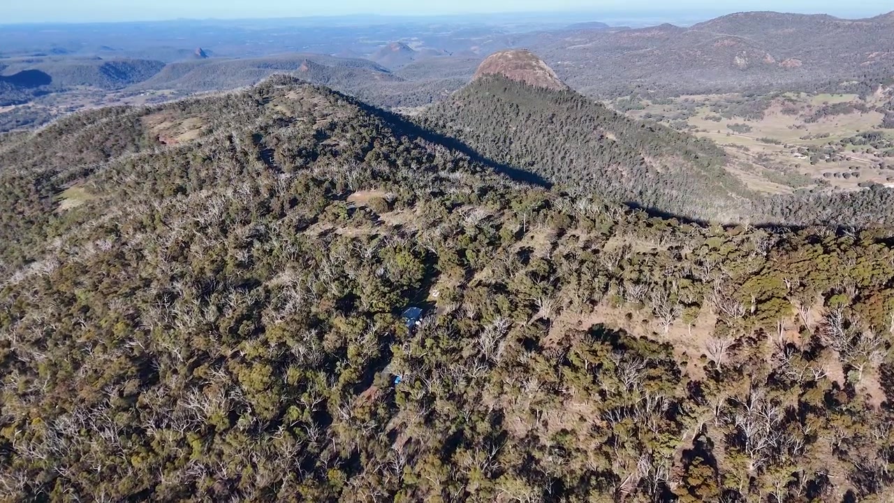 Ampia ripresa aerea con drone di cupole di telescopi in cima a montagne boscose nel Parco Nazionale Warrumbungle, Australia.