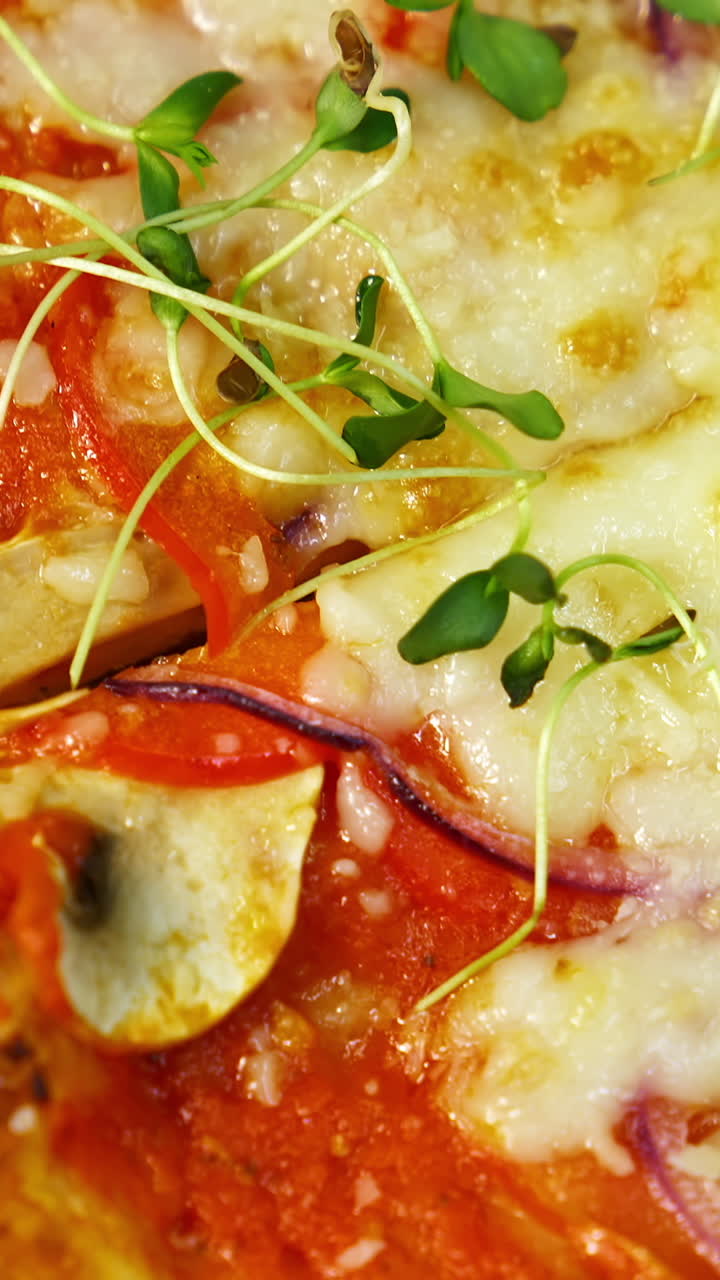 Appetizing pizza. Delicious pastry with bacon, onions, tomatoes and melted cheese. Green sprouts on ready pizza in the restaurant. Macro shot. Vertical video