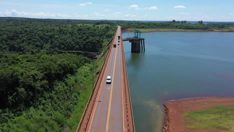 drone flying over an industrial highway that separates a dam from the jungle in misiones, argentina.