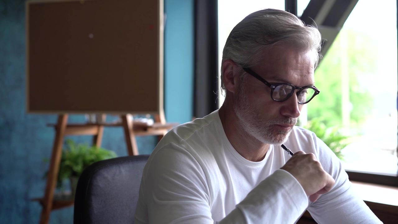 Mature Architect Reviewing and Marking Up Blueprints in Office