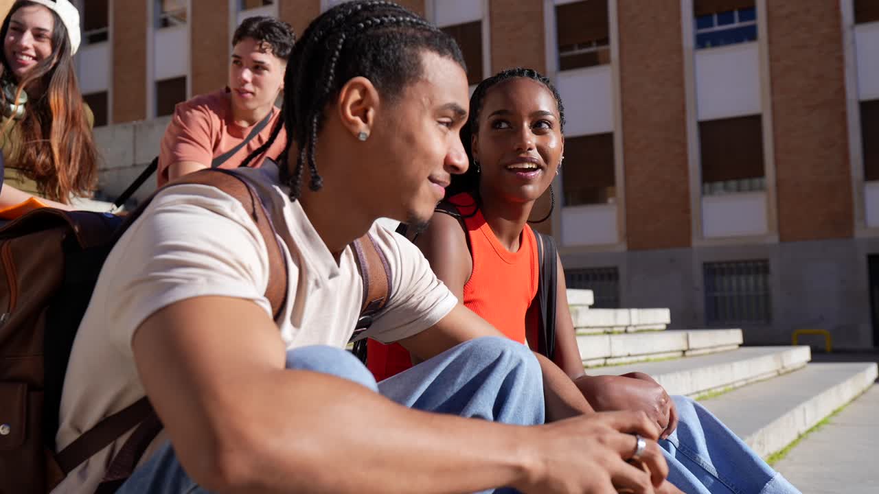 Groupe diversifié de jeunes étudiants discutant et souriant sur les marches de l'université