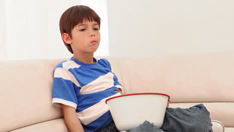 boy eating popcorn while he watches television