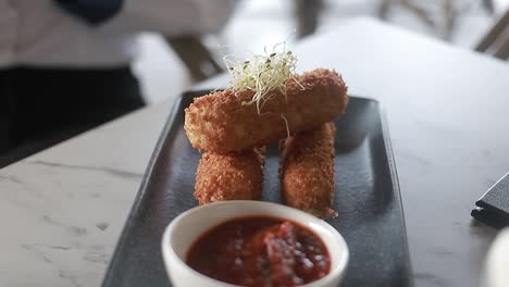 croquettes on a thin plate with its ketchu on the side, restaurant food, video detail