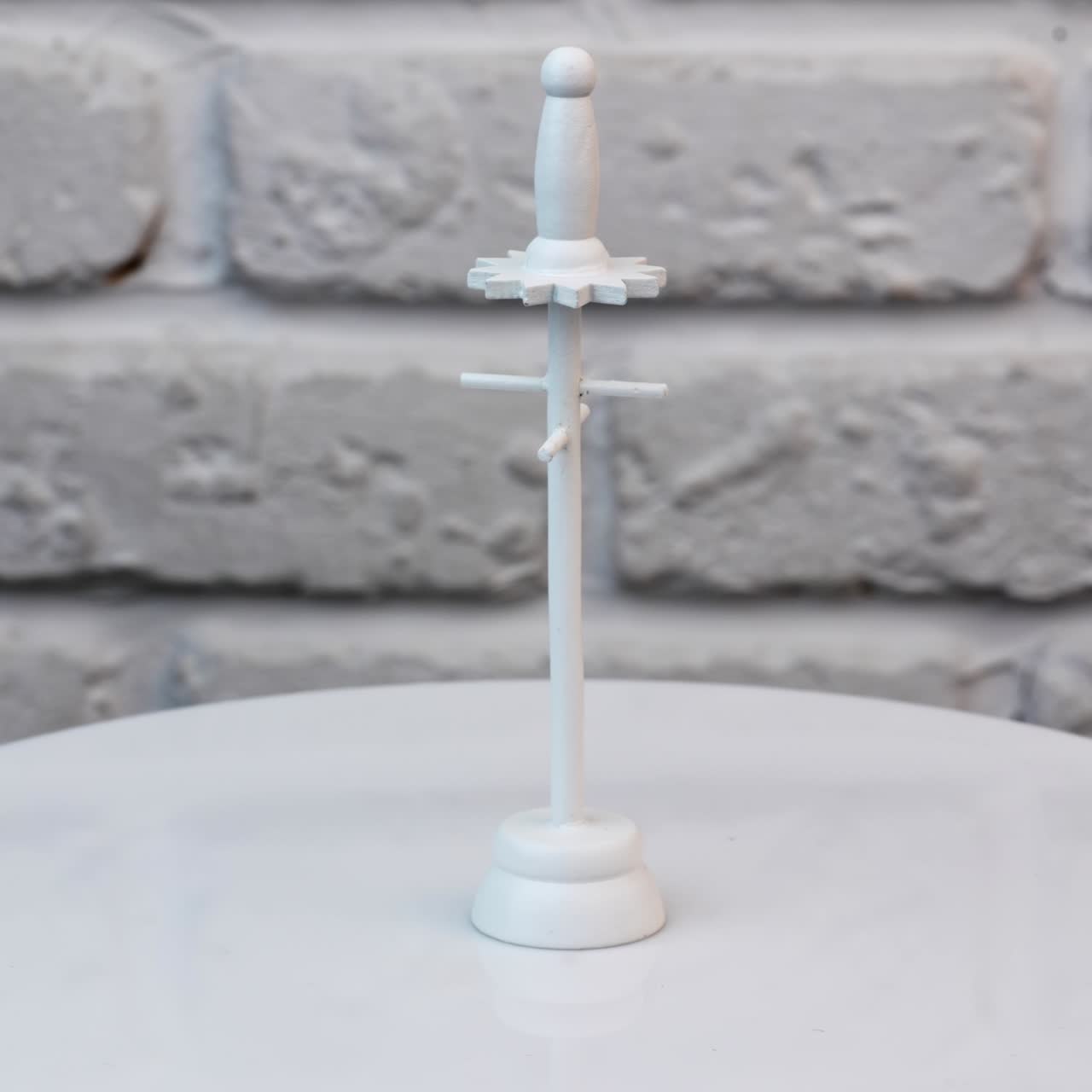 Miniature clothes rack made of wood. White hanger rotating at the table close up. White wall background