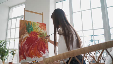 long haired lady at work upon wonderful painting of flowers