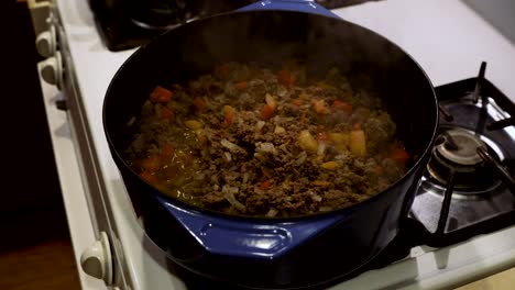 ground beef, onions, and bell peppers simmering in dutch oven on gas stove