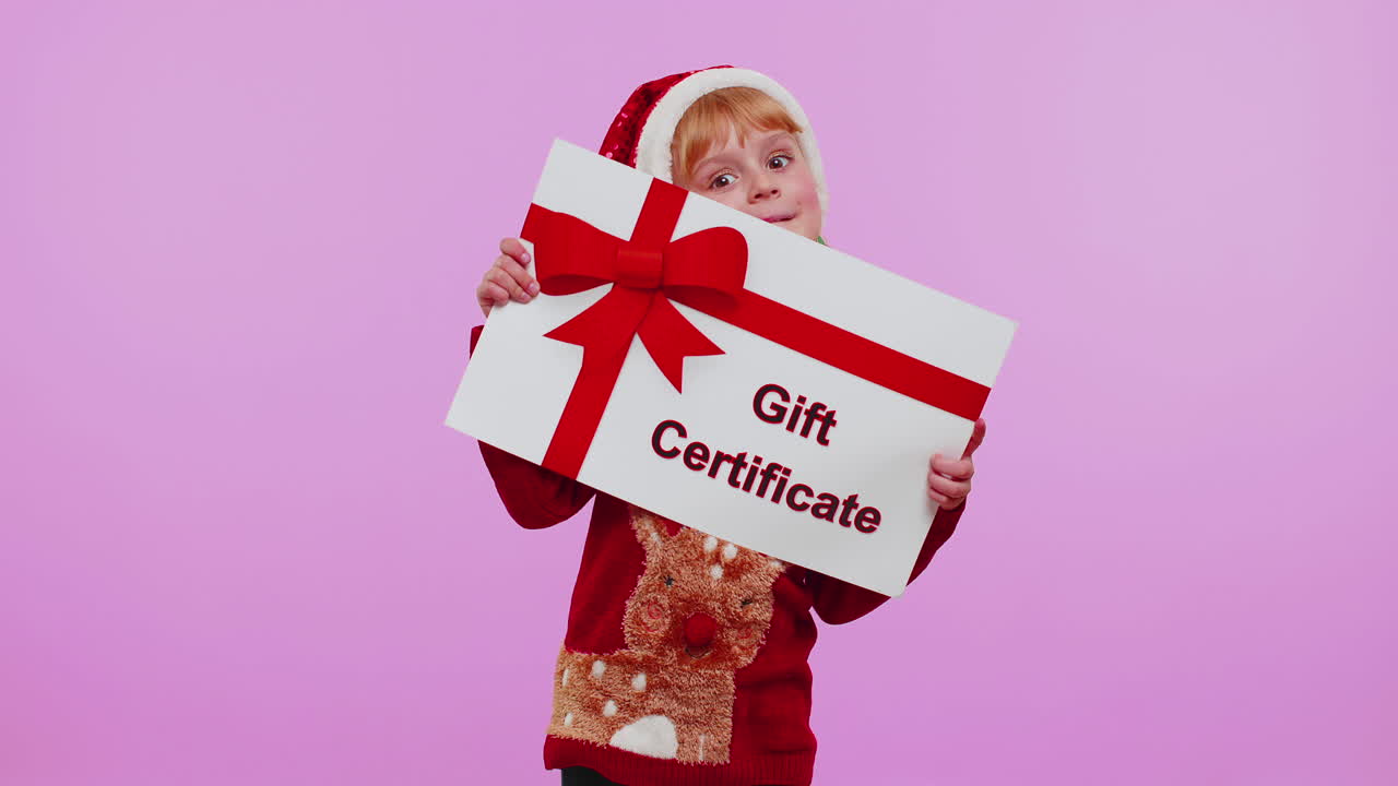 Ragazza divertente con cappello da Babbo Natale che presenta una carta regalo, un buono regalo, un coupon o un voucher vincitore.