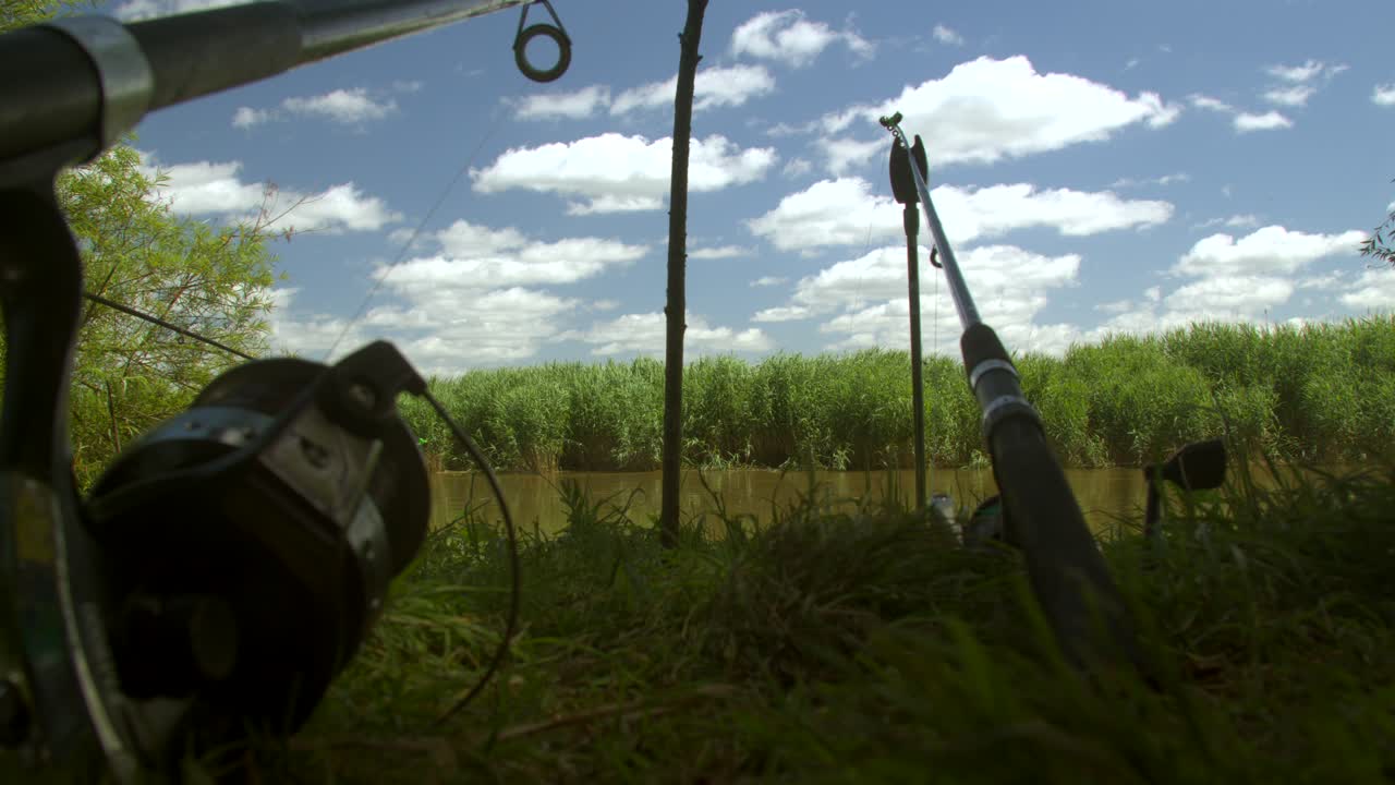 Low angle shot of two fishing rods on a bank of a river at fishing session