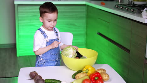 child chops veggies in kitchen. a toddler sorts colorful vegetables in a bright kitchen, focusing on ingredients in a large bowl for cooking