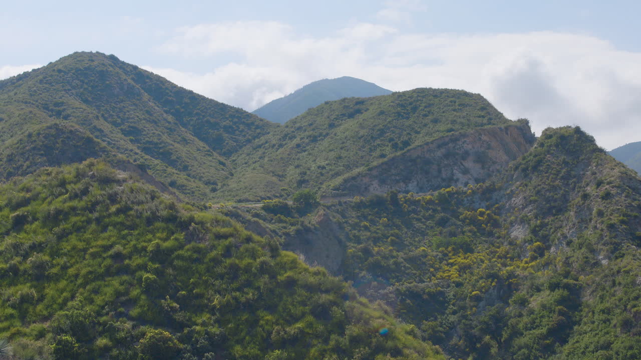 lapso de tiempo de nubes blancas moviéndose sobre una exuberante cordillera verde ubicada en echo mountain trails california