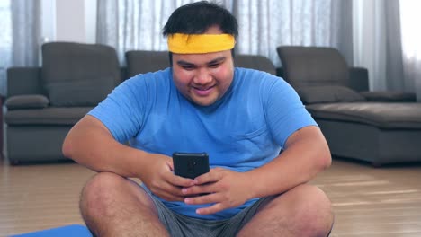 overweight man doing home workout and using phone