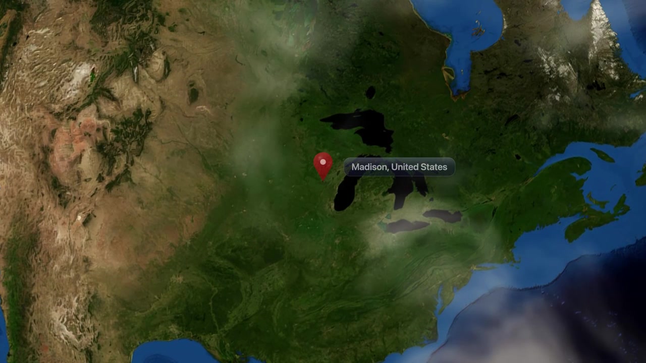 Satellite animation zooms from deep space orbit into North America, pinpointing Madison, Wisconsin, United States. Includes NASA public domain imagery.