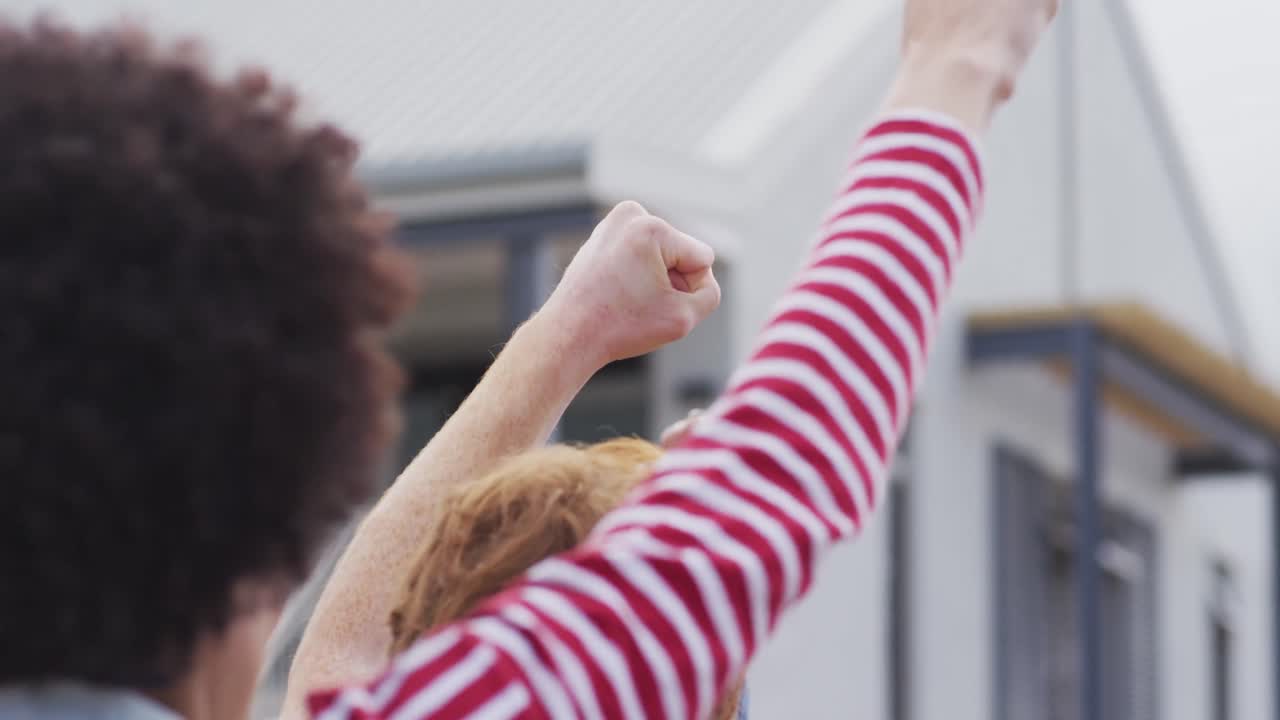 vista posterior de un grupo diverso de manifestantes con las manos levantadas gritando