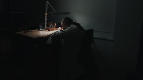 a professional watchmaker working through the night repairing - wide shot