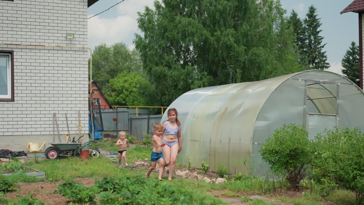 Siblings Dash Towards Backyard Pool With Joy, Brothers And Sister Playfully Run Near Garden In Summer, Young Siblings Excitedly Race Across Grassy Yard Towards Swimming Pool Amid Lush Plants