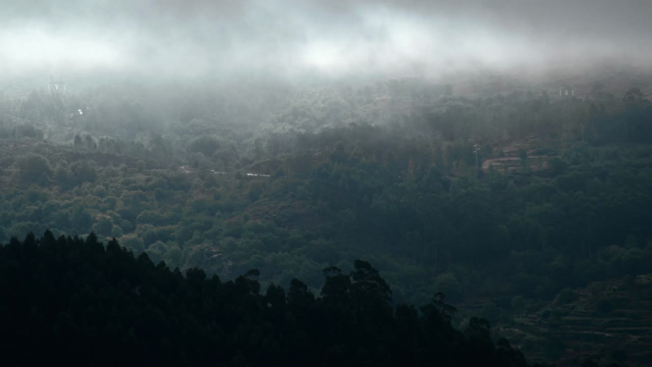 4K timelapse of clouds rolling through a forested mountain range while the sun peeks through from time to time