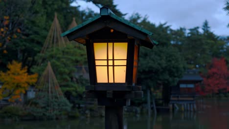a traditional japanese lantern glows softly in the night, illuminating the peaceful paths of kanazawa’s kenroku-en gardens.