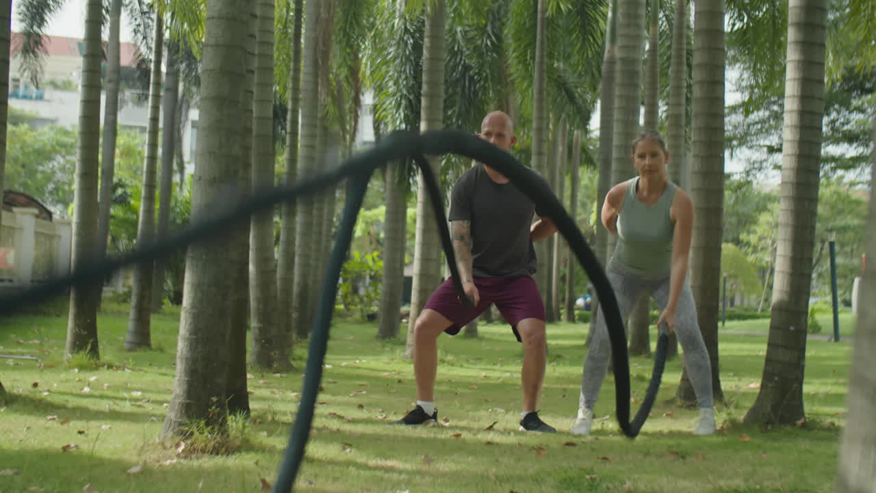 Sporty Couple Having Battle Rope Workout Together in Park