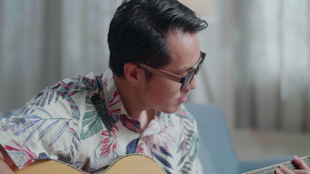 집에서 기타를 연주하고 노트북에 음악을 작곡하는 아시아인 작곡가의 클로즈업