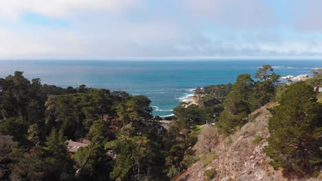 Cars-driving-by-coastal-canyon-homes-near-bridge-next-to-Carmel-By-The-Sea-Big-sur-neighborhood