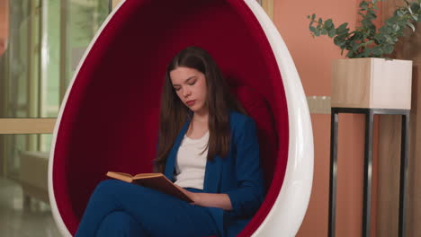 young woman relaxing in a chair and reading a book