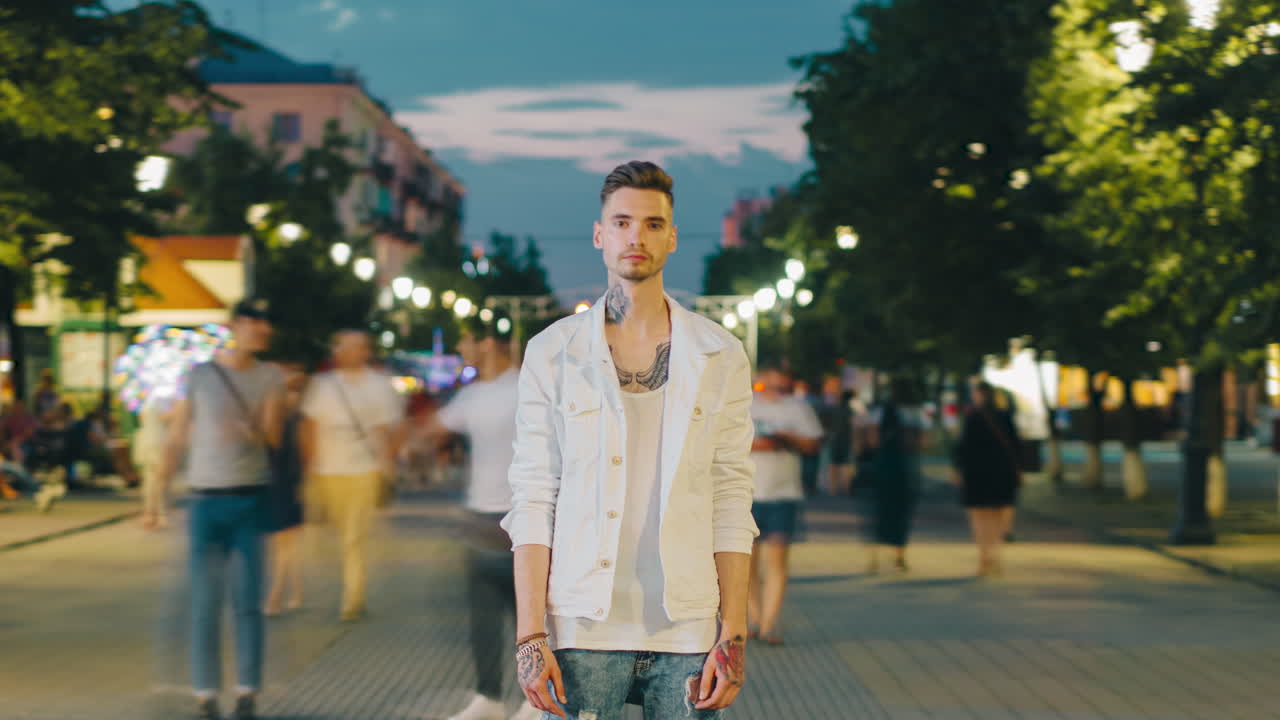 Young Man in a White Jacket on a City Street at Night