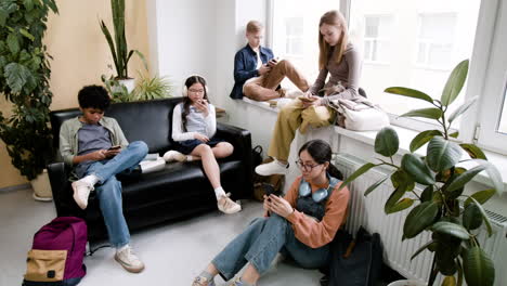 teenagers engaged with smartphones in a casual indoor setting