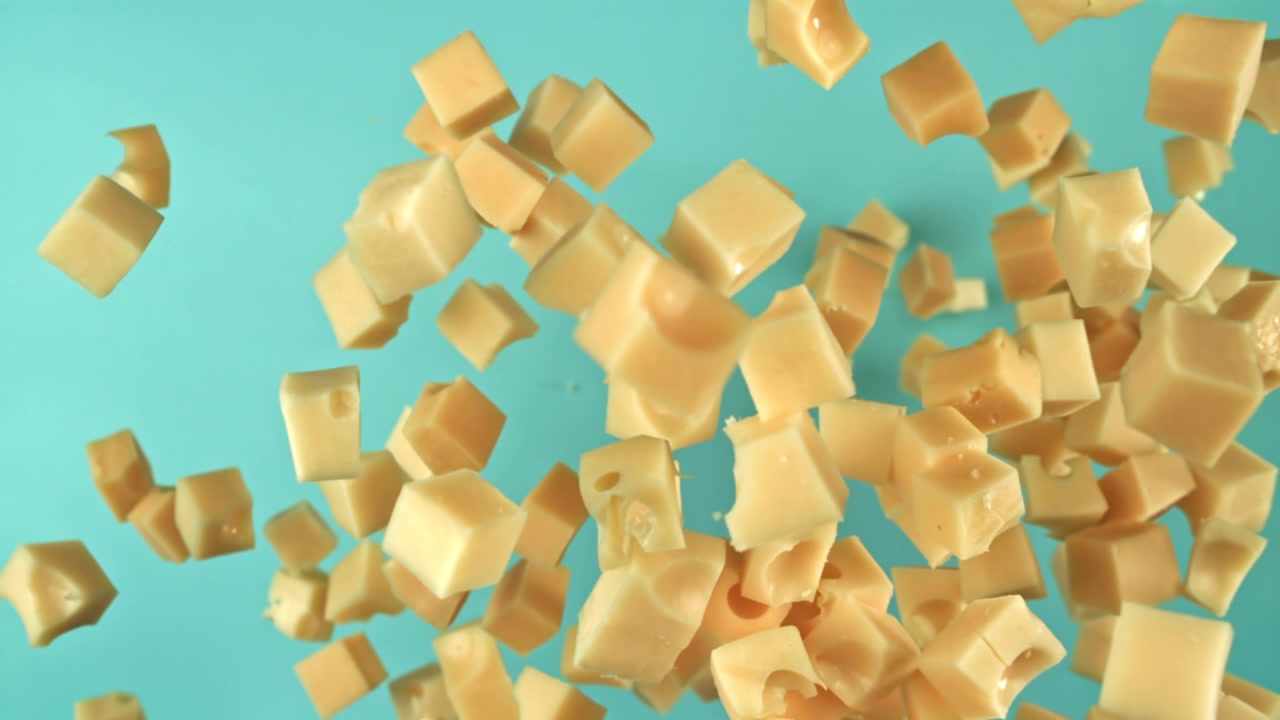 Dés de fromage tombant au ralenti sur un fond bleu