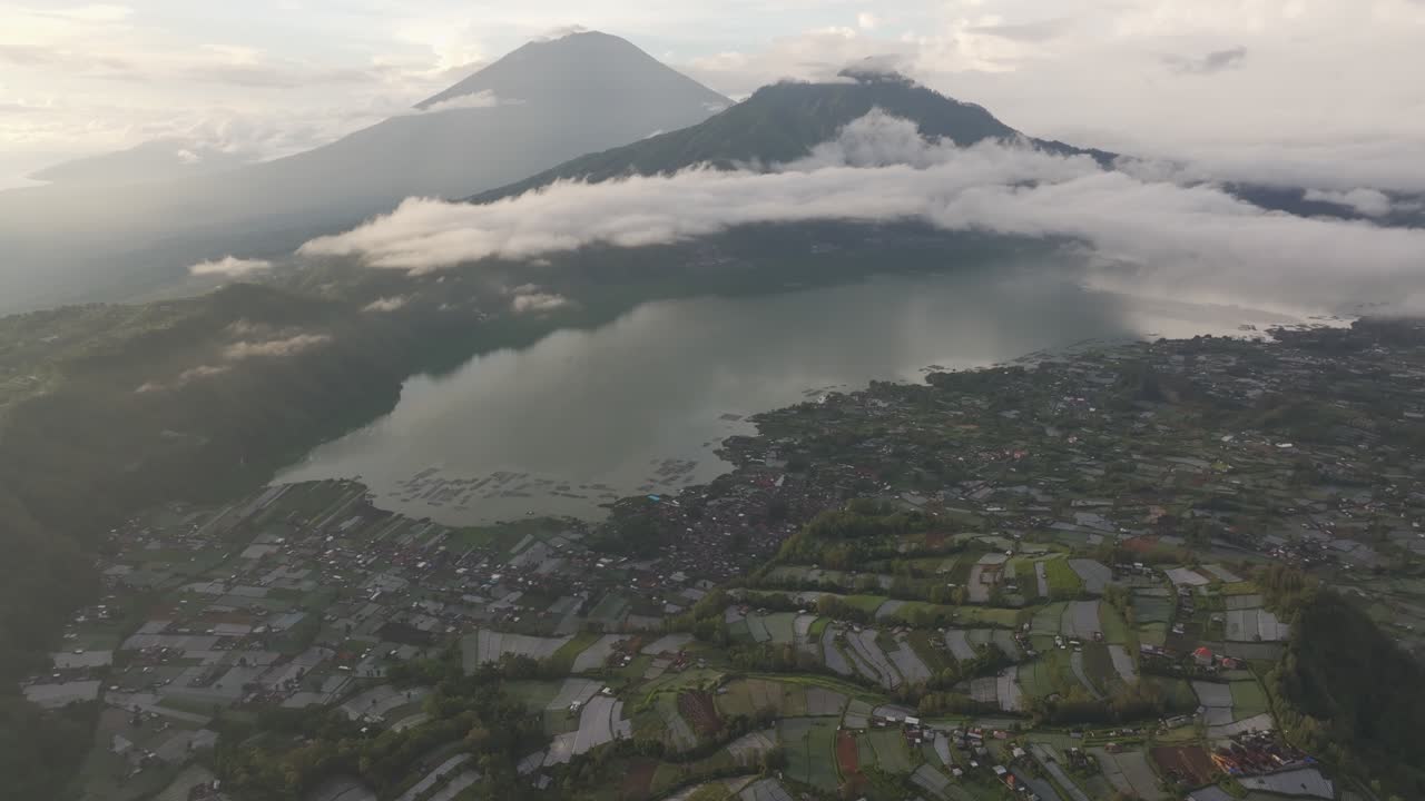 Pemandangan udara matahari terbit di puncak gunung berapi, lahan pertanian, dan danau berkabut, Indonesia