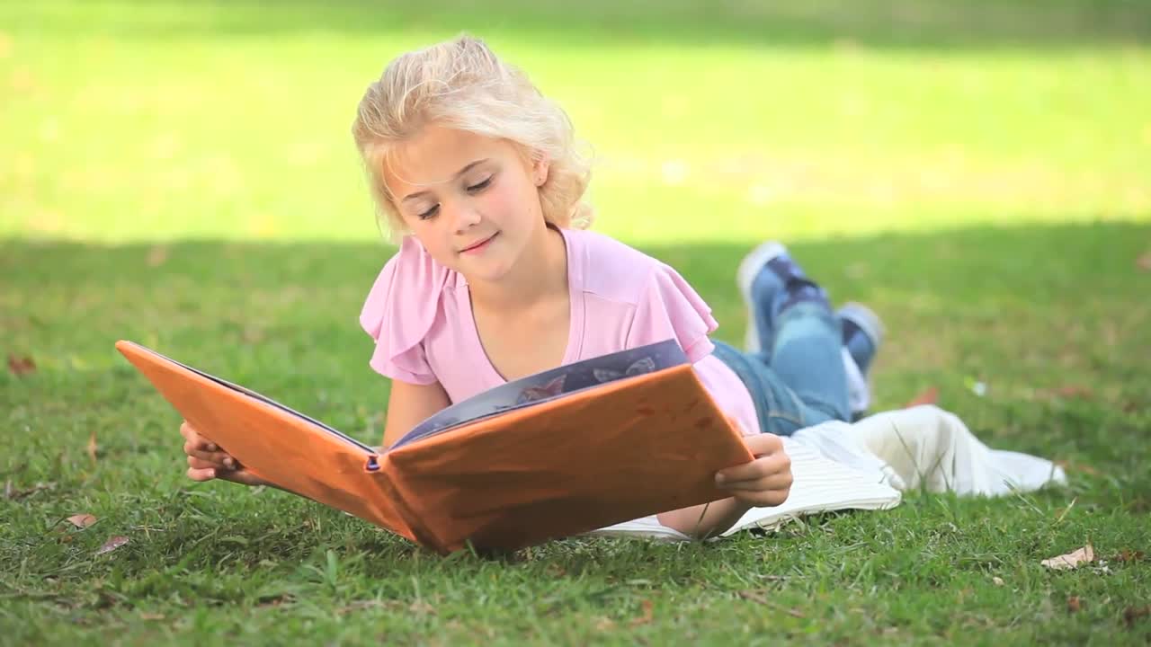 Giovane ragazza che legge un libro all'aperto