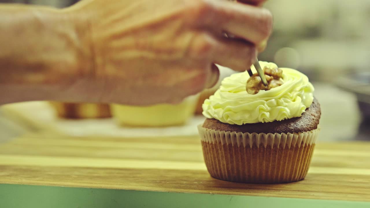 Chef che guarnisce cupcake con le noci