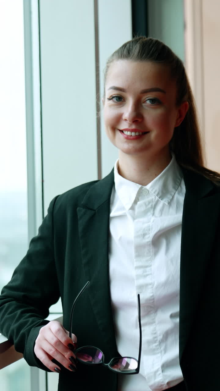 Caucasian woman in black jacket standing at the window in office