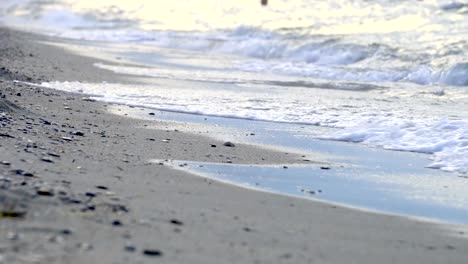 ow point of view over an out-of-focus pebbled beach with a splashing wave, background loop