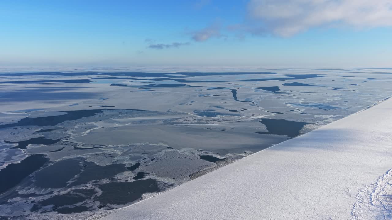 Lunga costa ghiacciata che si estende attraverso una tranquilla regione costiera invernale, panoramica aerea a sinistra.