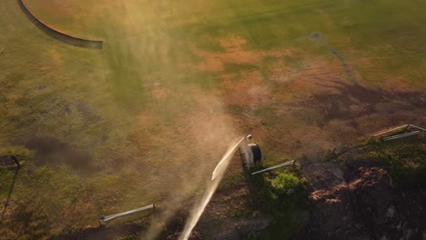 Aerial-top-view-of-sprinkler-watering-grass-field-of-racecourse-hippodrome-after-hot-summer