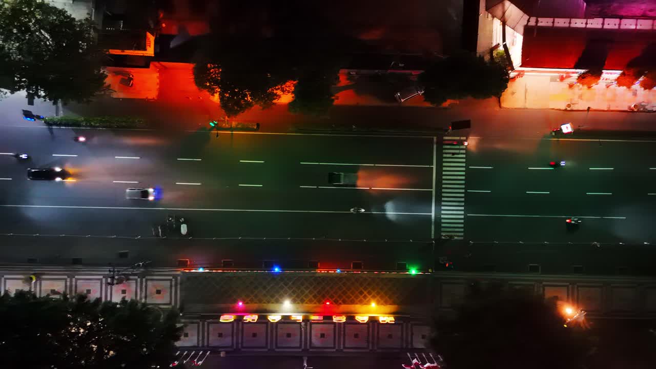 Overhead drone view of vehicle crossing on the city street in the night. 4K aerial view.