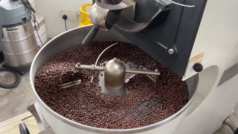 coffee beans roasting and cooling down on the plate of the machine, commodity price increase, supply chain inflation concept