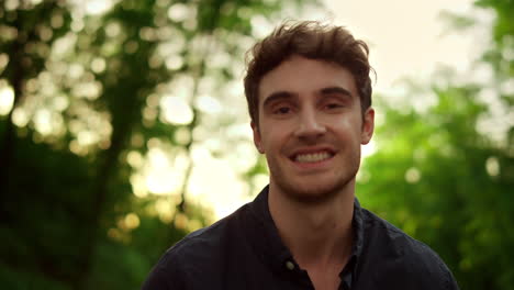 Charming-man-looking-at-camera-outdoors.-Attractive-male-person-posing-on-road