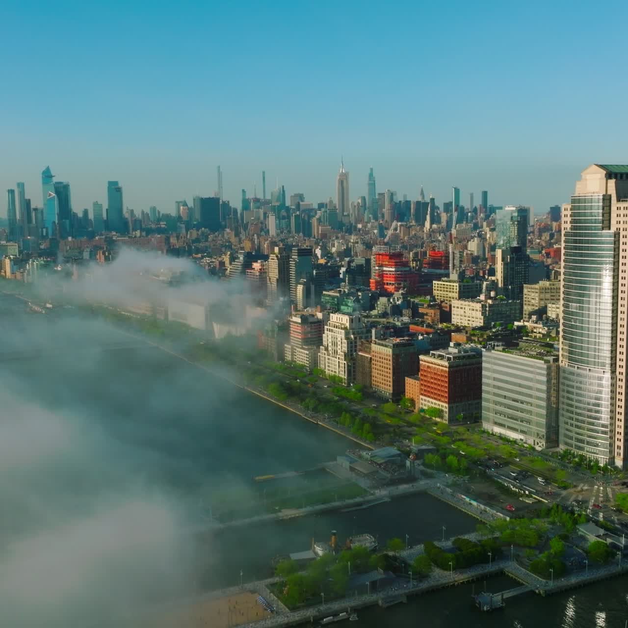 White thick smoke coming closer to the Manhattan Island. Amazing New York cityscape lit with sunshine