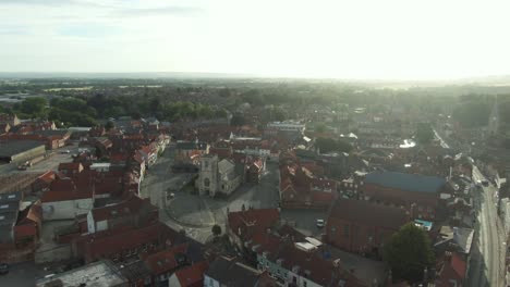 Drone-shot-pushing-in-to-historic-English-market-town-centre-with-church-at-golden-hour-sunrise